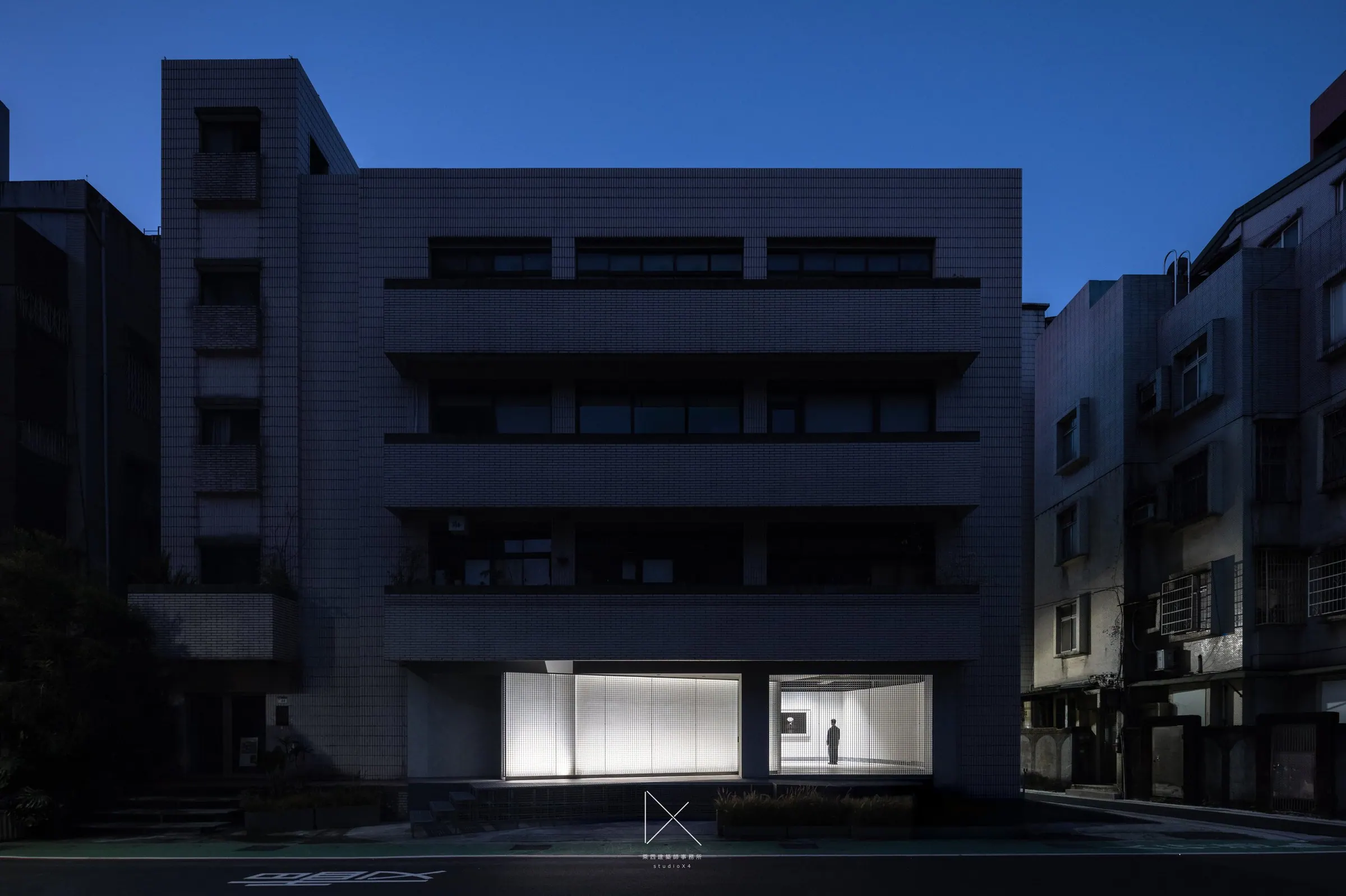 夜間建築正立面，一樓展間燈光點亮整棟量體。