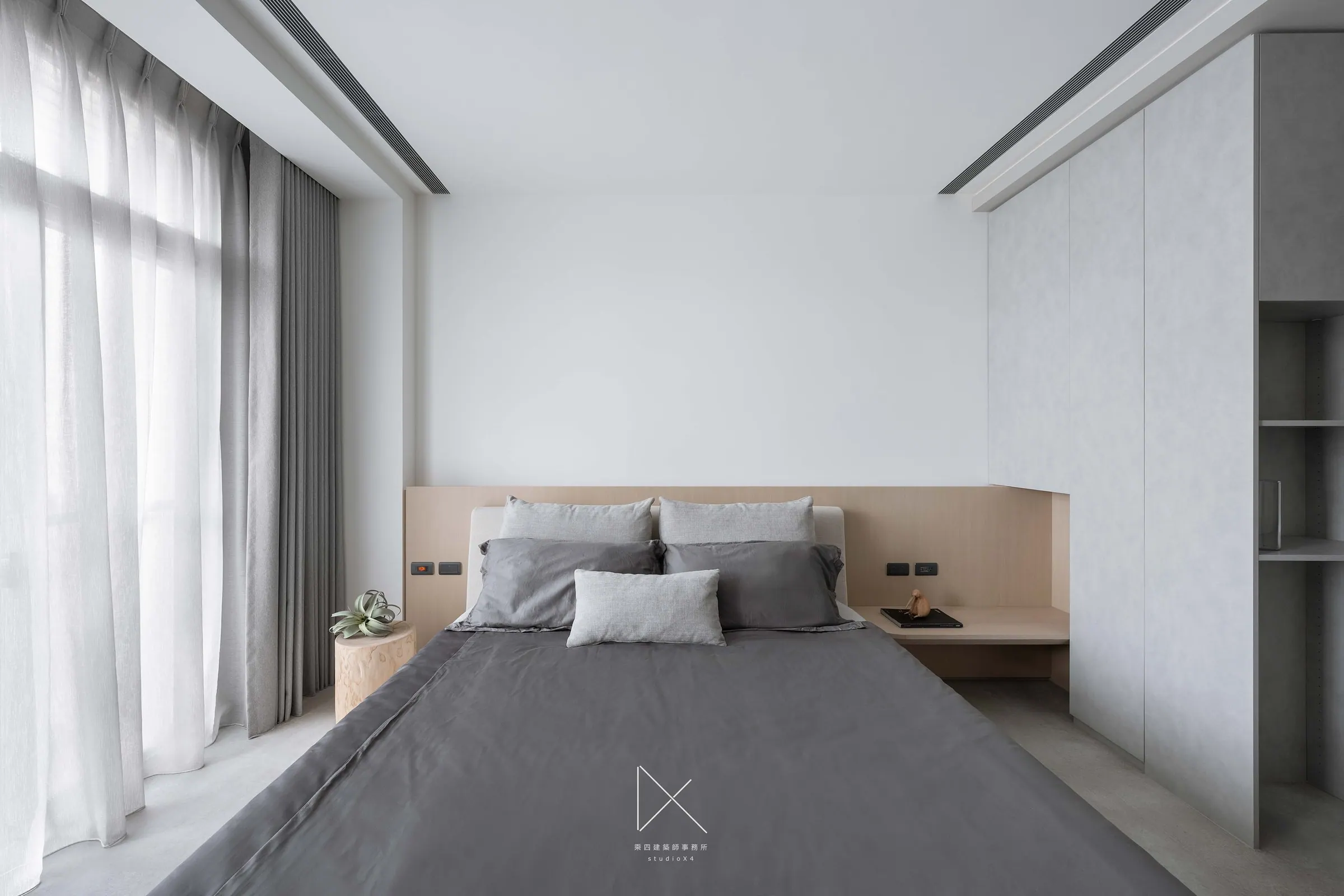 The master bedroom is calibrated by a cantilevered bedside ledge and a flush wardrobe wall — grey carries the room.