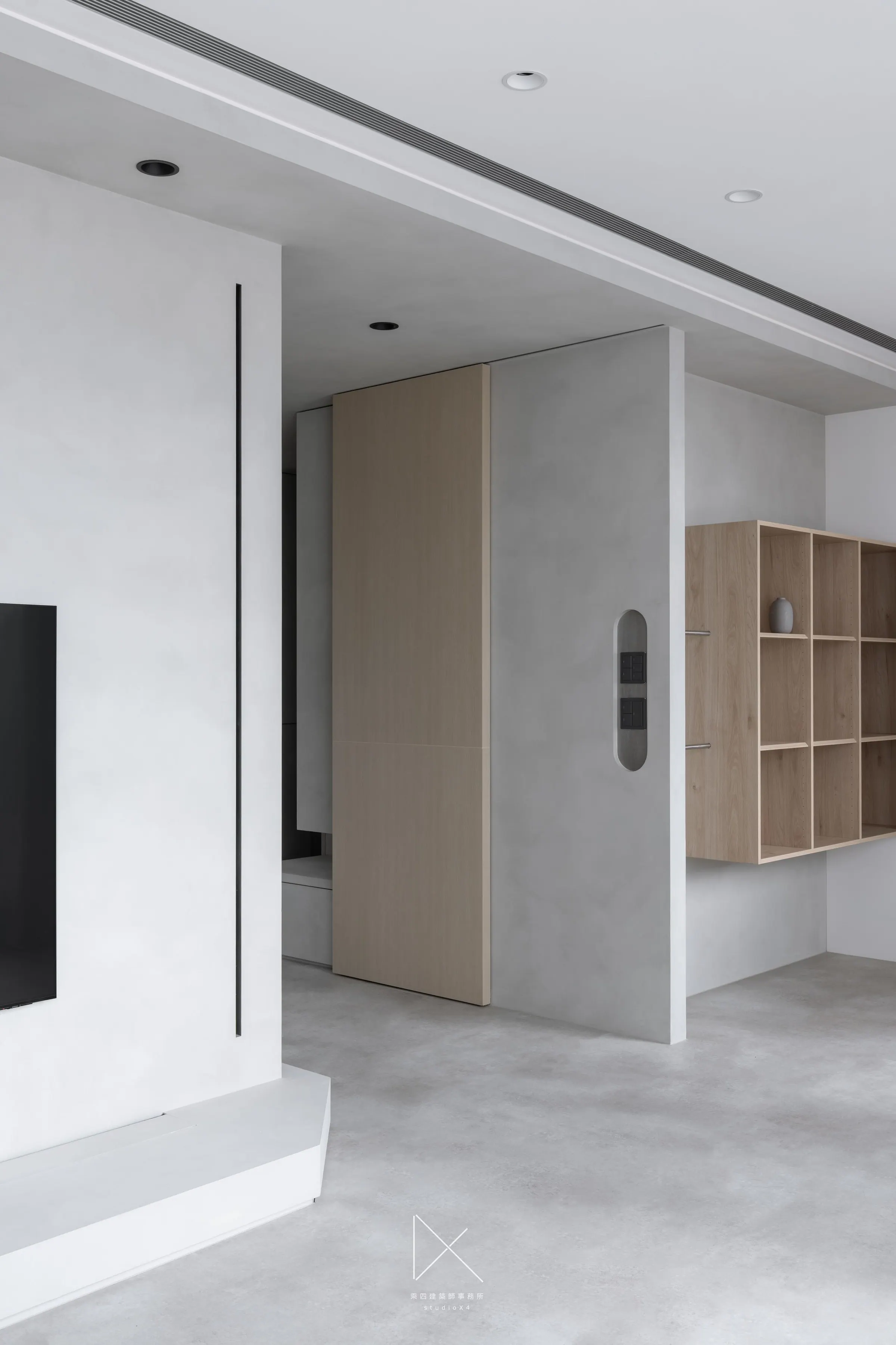 The entry resolves into a circular pull and a hidden door — the elevation absorbs every threshold.